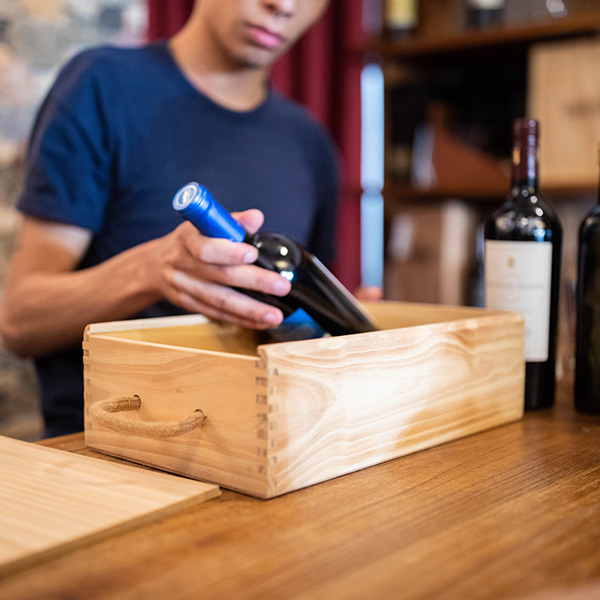 salesman packing a wine bottle in wooden box